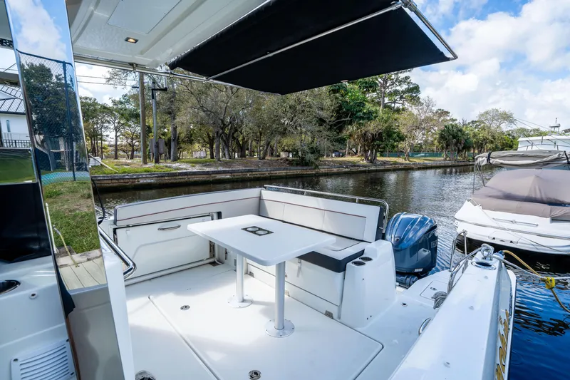Slide: The Image of 2024 Jeanneau Leader 10.5 WA Series 2 boat interior with seating and table by the water. - 51