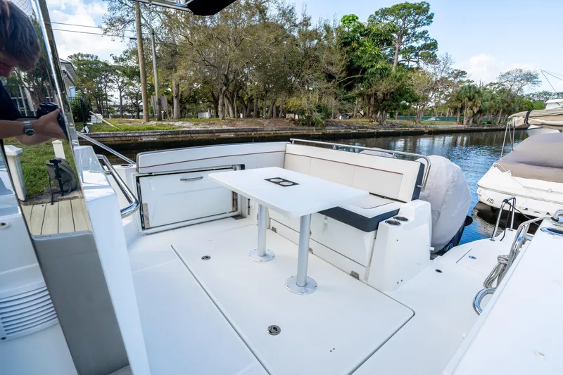 Slide: The Image of 2024 Jeanneau Leader 10.5 WA Series 2 boat interior with seating and table by the water. - 62