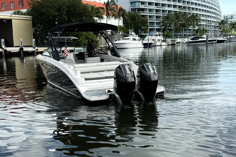 Slide: The Image of 2021 Sea Ray SDX 290 Outboard boat docked in a marina with modern buildings. - 14