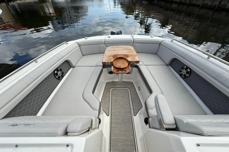 Slide: The Image of 2021 Sea Ray SDX 290 Outboard boat interior with seating and wooden table on calm water. - 25
