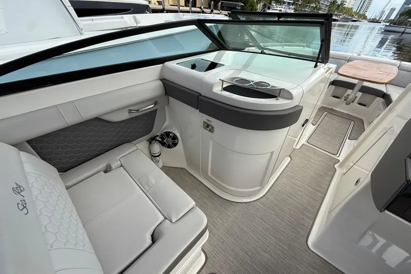 Slide: The Image of 2021 Sea Ray SDX 290 Outboard interior with seating and table, docked by the water. - 36