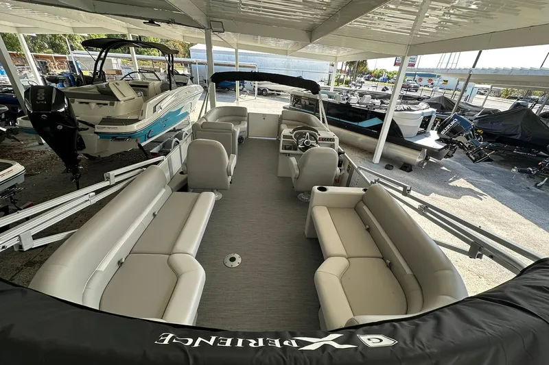 Slide: The Image of 2026 Sweetwater EX2286SBX pontoon boat with spacious seating, docked under a covered area. - 26
