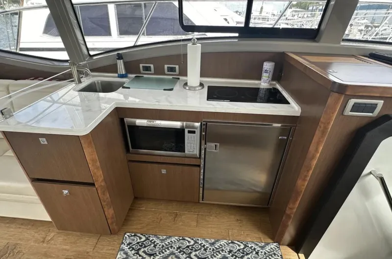 Slide: The Image of Modern kitchen area in a 2018 Sea Ray Sundancer 400 yacht with appliances and wood cabinetry. - 6