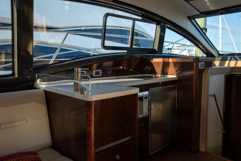 Slide: The Image of Interior of 2018 Sea Ray Sundancer 400 yacht, featuring a modern kitchenette and seating area. - 9