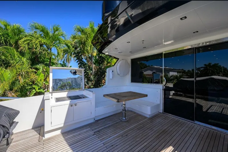 Slide: The Image of Luxurious 2014 Hampton Fly yacht deck with outdoor kitchen and seating, surrounded by lush greenery. - 40