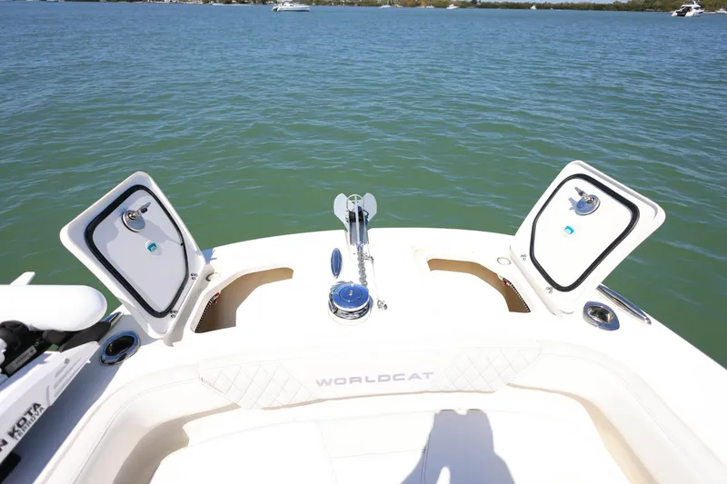 Slide: The Image of 2025 World Cat 235 TE boat deck with open storage compartments on calm water. - 16