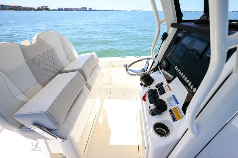 Slide: The Image of 2025 World Cat 235 TE boat interior with helm and seating, overlooking calm waters. - 19