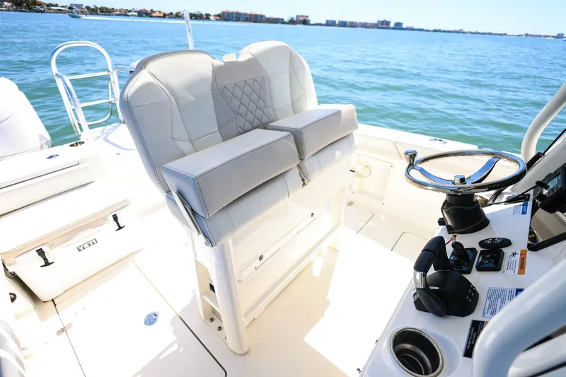 Slide: The Image of 2025 World Cat 235 TE boat interior with helm and seating, overlooking calm waters. - 20