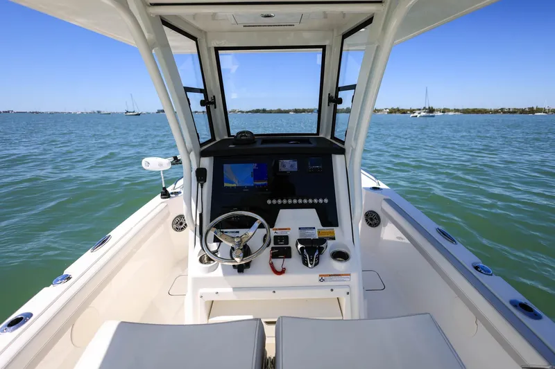 Slide: The Image of 2025 World Cat 235 TE boat cockpit with steering wheel and navigation system on calm water. - 9