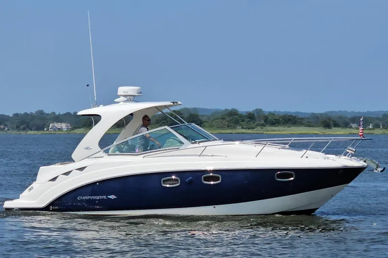 The Image of 2015 Chaparral 310 Signature boat cruising on a calm lake with scenic background. - 0