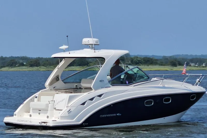 Slide: The Image of 2015 Chaparral 310 Signature boat cruising on a calm lake with scenic background. - 4