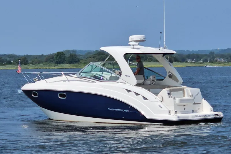 Slide: The Image of 2015 Chaparral 310 Signature boat cruising on a calm lake with scenic background. - 8