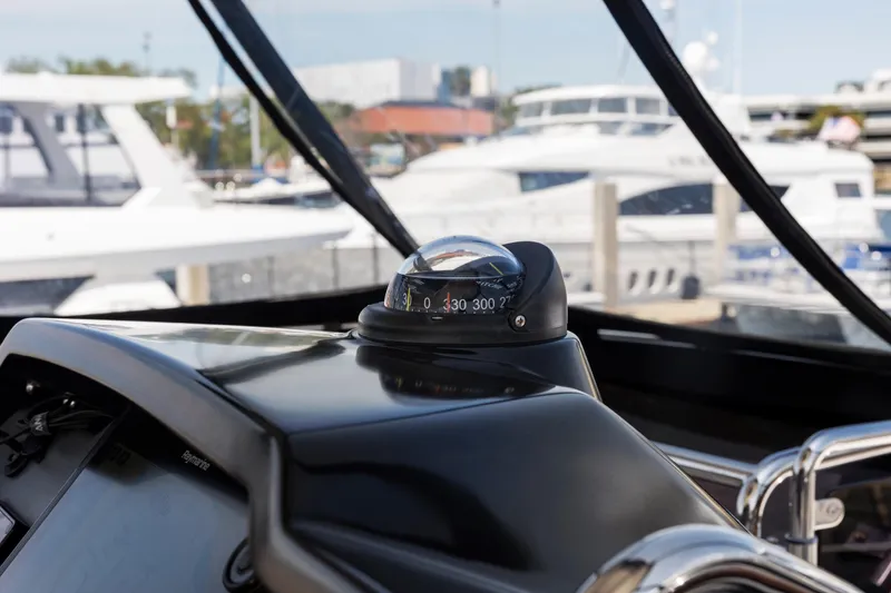 Slide: The Image of Compass on the helm of a 2022 Aquila 44 Yacht, docked at a marina. - 52