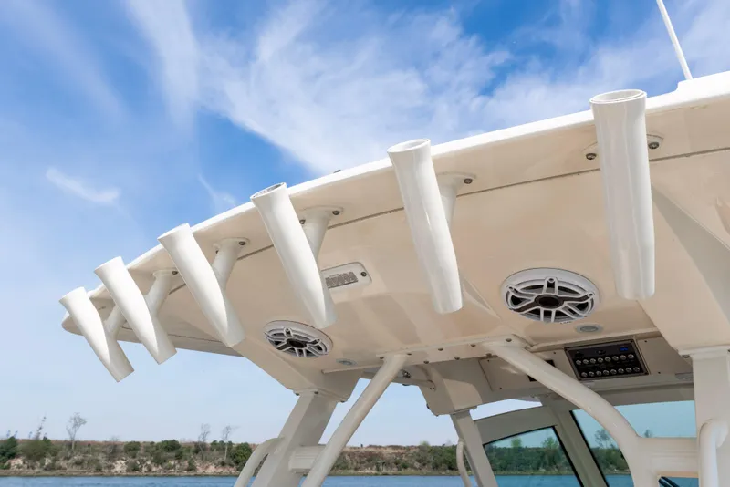 Slide: The Image of 2020 Scout 355 LXF boat roof with rod holders and speakers under blue sky. - 19