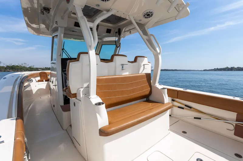 Slide: The Image of 2020 Scout 355 LXF boat interior with tan seating, on calm water. - 9