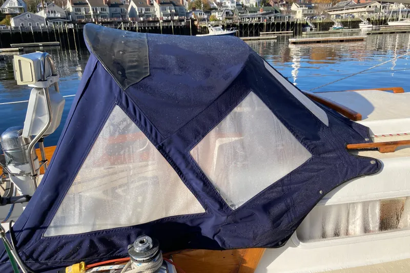 Slide: The Image of 1971 Luders 33 sailboat with blue canvas cover, docked near coastal town. - 7