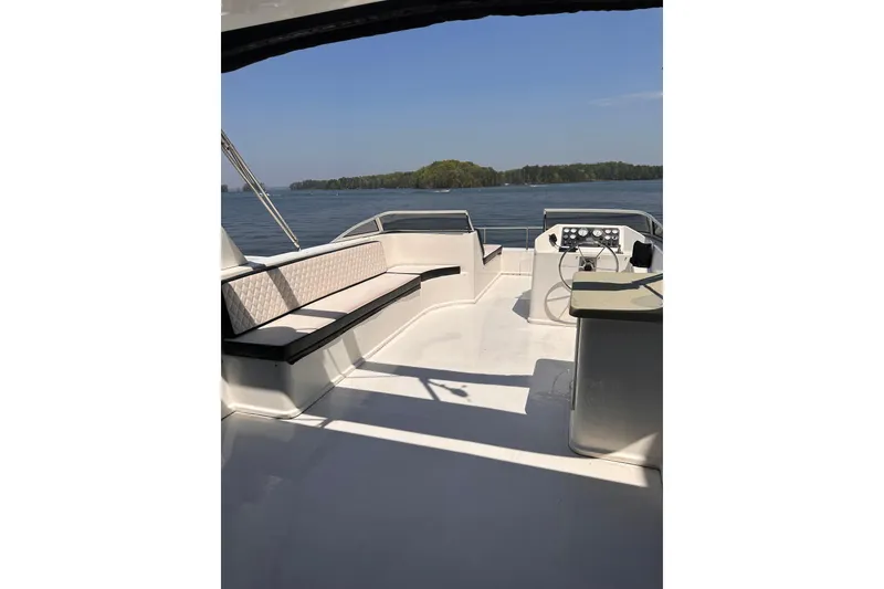 Slide: The Image of Starlite 18x85 houseboat interior, 2008 model, featuring spacious seating and steering area on a lake. - 18