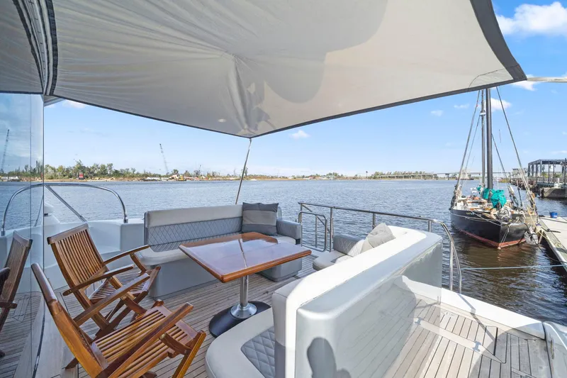 Slide: The Image of Luxurious 2010 Mangusta 72 Express yacht deck with seating and table, overlooking serene waters. - 9