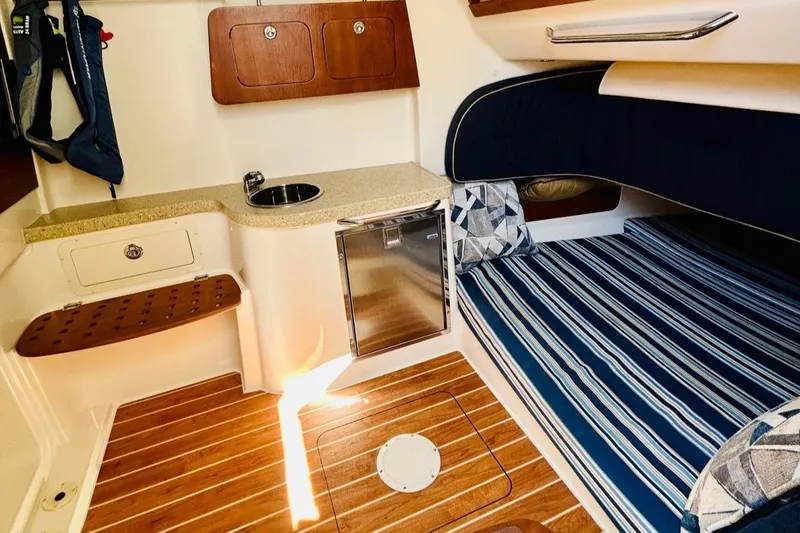 Slide: The Image of 2012 Grady-White Canyon 366 cabin interior with striped bedding and compact kitchenette. - 40