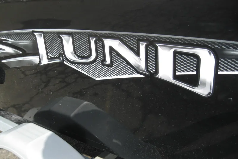 Slide: The Image of Close-up of 2015 Lund 1650 Rebel XL Tiller logo on black surface. - 2