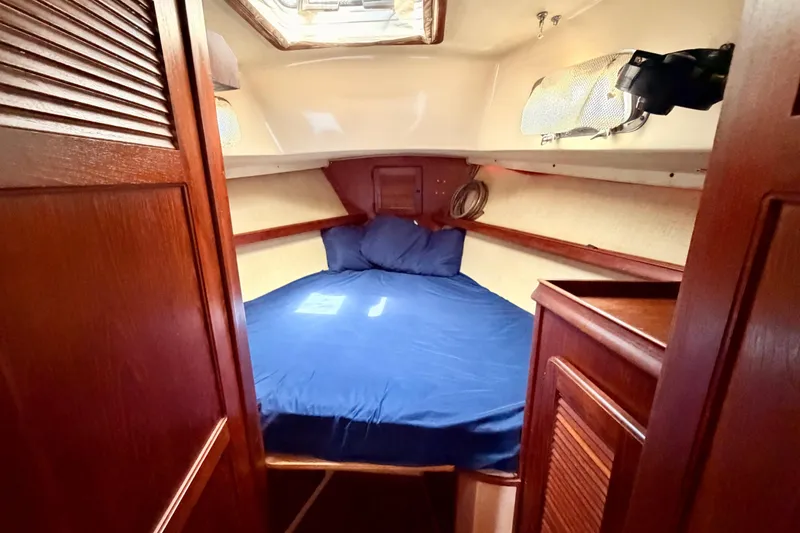 Slide: The Image of 1989 Island Packet Cutter cabin with blue bedding and wooden interior. - 11