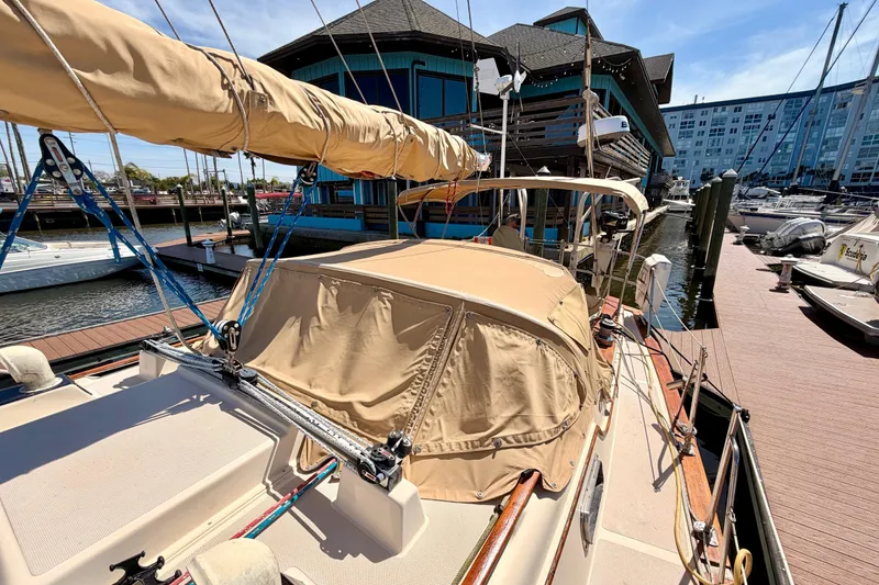 Slide: The Image of 1989 Island Packet Cutter sailboat docked at marina with tan canvas cover. - 20