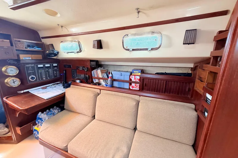 Slide: The Image of 1989 Island Packet Cutter interior with navigation station, beige sofa, and storage shelves. - 6