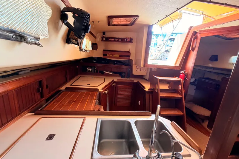 Slide: The Image of Interior of 1989 Island Packet Cutter sailboat, featuring a compact kitchen with wooden cabinetry. - 9