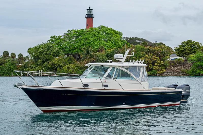 The Image of 2019 Hunt Yachts Surfhunter 32 cruising near a lush green island with a lighthouse. - 0