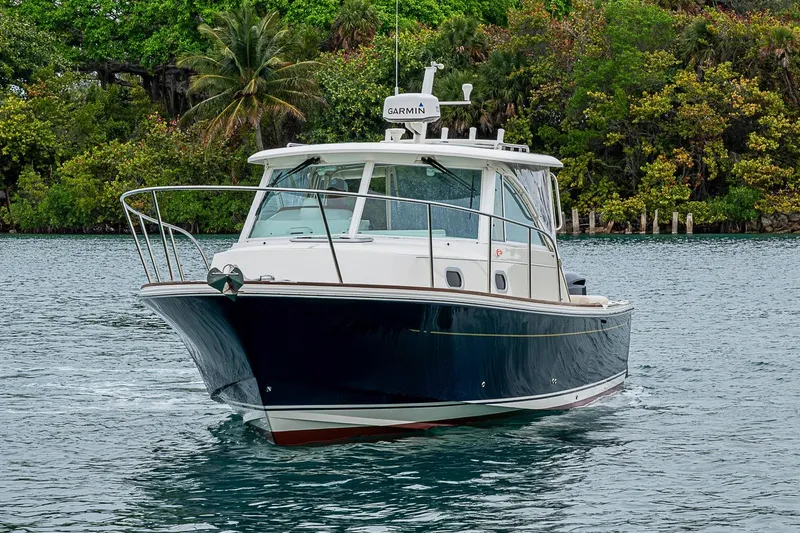 Slide: The Image of 2019 Hunt Yachts Surfhunter 32 cruising on water, surrounded by lush greenery. - 11