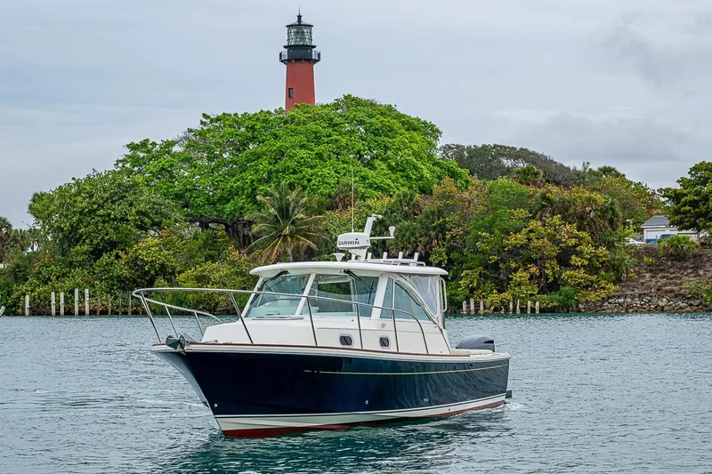 Slide: The Image of 2019 Hunt Yachts Surfhunter 32 cruising near a lush island with a lighthouse. - 12