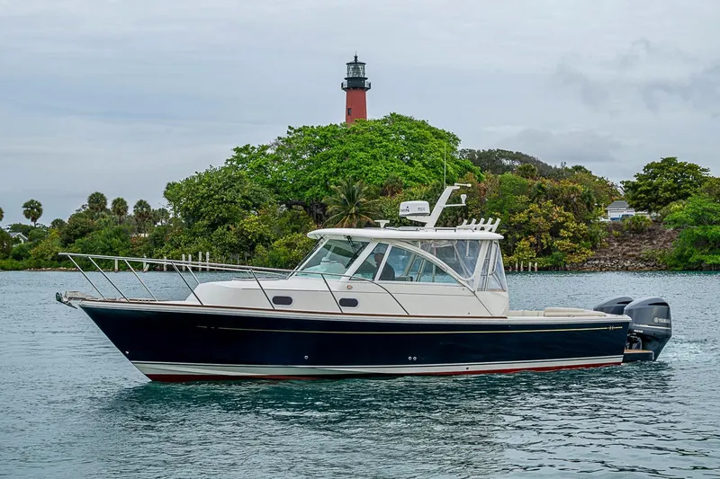 Slide: The Image of 2019 Hunt Yachts Surfhunter 32 cruising near a lighthouse, surrounded by lush greenery. - 13
