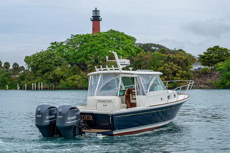 Slide: The Image of 2019 Hunt Yachts Surfhunter 32 cruising near a lighthouse, featuring twin Yamaha engines. - 17