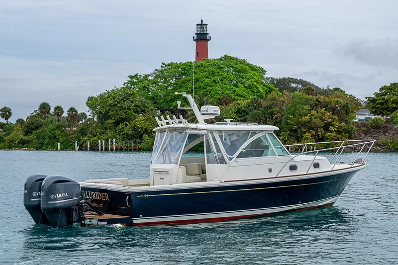 Slide: The Image of 2019 Hunt Yachts Surfhunter 32 cruising near a lighthouse, featuring twin Yamaha engines. - 19