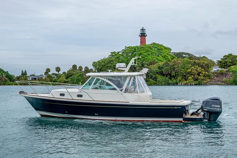 Slide: The Image of 2019 Hunt Yachts Surfhunter 32 cruising near a lush, green shoreline with a lighthouse. - 2