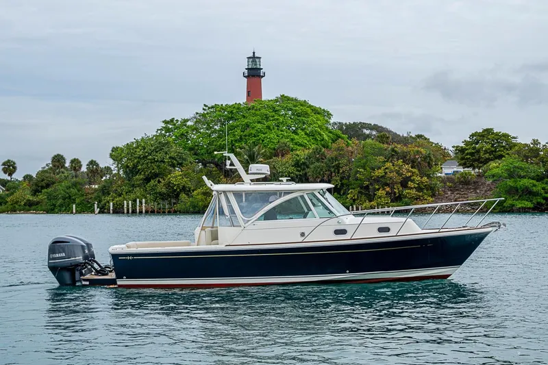 Slide: The Image of 2019 Hunt Yachts Surfhunter 32 cruising near a lush island with a lighthouse. - 21
