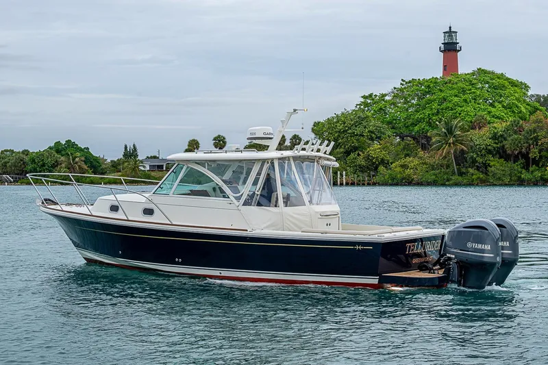 Slide: The Image of 2019 Hunt Yachts Surfhunter 32 cruising near a lush, green shoreline with a lighthouse. - 3