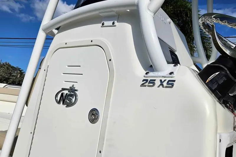 Slide: The Image of 2018 NauticStar 25 XS boat console with logo and model name, under clear blue sky. - 12