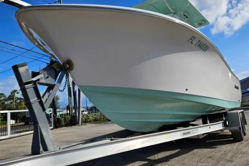 Slide: The Image of 2018 NauticStar 25 XS boat on trailer, viewed from the front, under a clear sky. - 2