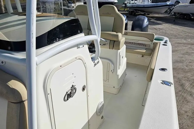 Slide: The Image of 2018 NauticStar 25 XS boat interior with seating and console, parked on a lot. - 6