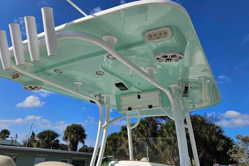 Slide: The Image of 2018 NauticStar 25 XS boat T-top with rod holders and speakers against blue sky. - 7