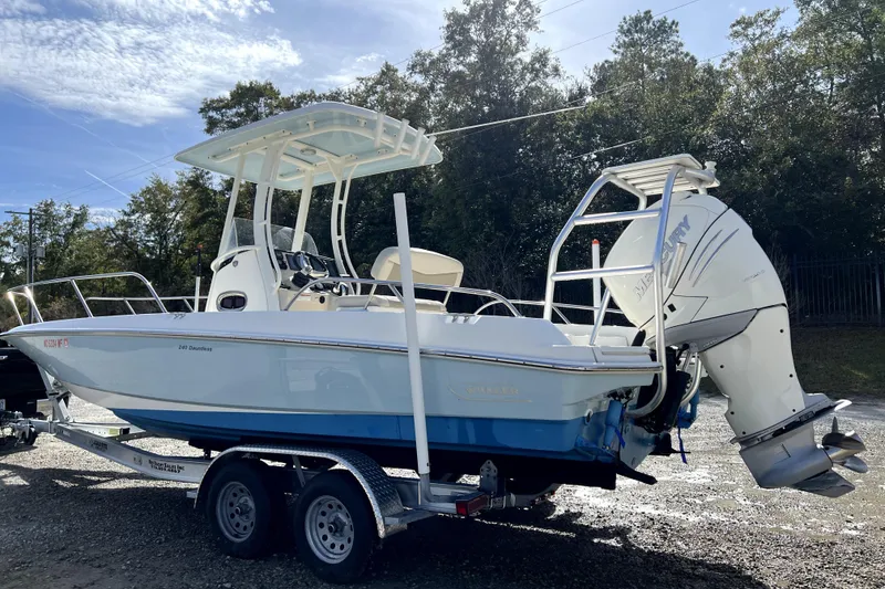 Slide: The Image of 2018 Boston Whaler 240 Dauntless boat on trailer, parked outdoors under clear sky. - 2