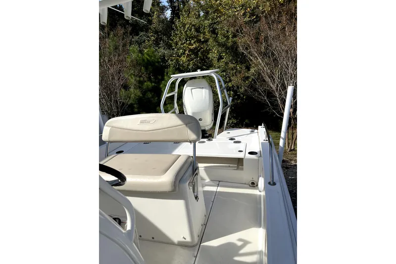 Slide: The Image of 2018 Boston Whaler 240 Dauntless boat interior with seating and console, surrounded by trees. - 8