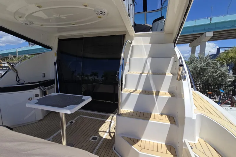Slide: The Image of 2007 Cruisers Yachts 447 Sport Sedan deck with stairs and table, under a clear sky. - 19