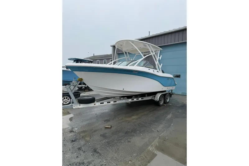 The Image of 2019 Sea Fox 226 Traveler boat on trailer, parked outdoors near a blue building. - 0