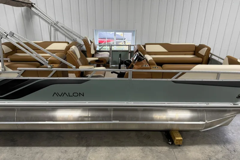 Slide: The Image of 2026 Avalon Venture Quad Lounge 19' pontoon boat with tan seating in a showroom. - 4