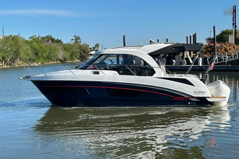 Slide: The Image of 2022 Beneteau Antares 9 boat cruising on a calm river near a marina. - 10
