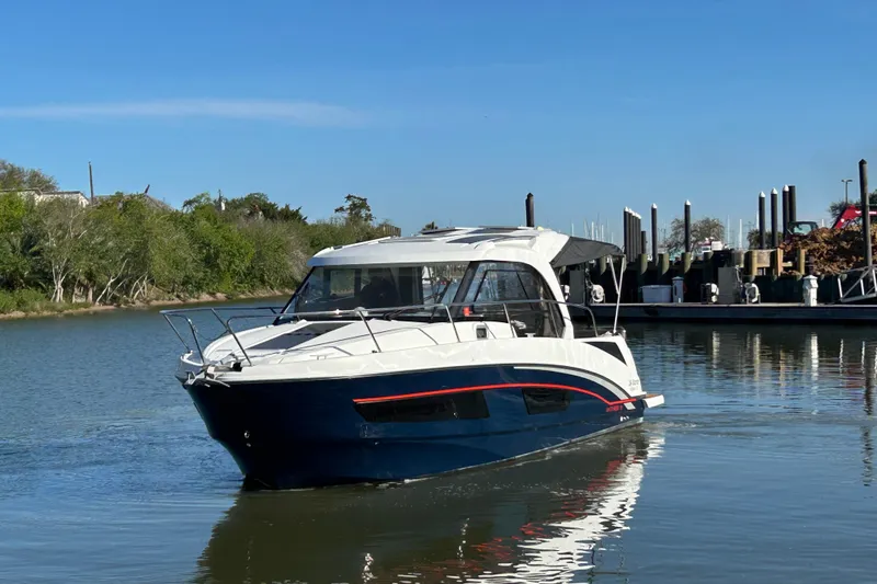 Slide: The Image of 2022 Beneteau Antares 9 boat cruising on a calm river near a marina. - 13
