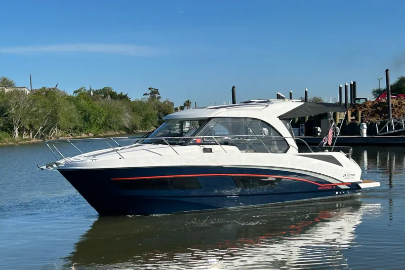 Slide: The Image of 2022 Beneteau Antares 9 boat on calm water, dock and trees in background. - 14