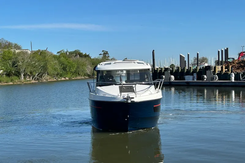 Slide: The Image of 2022 Beneteau Antares 9 boat cruising on a calm river near a marina. - 16